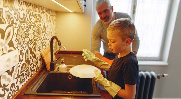 A child helping washing dishes to contribute to family chores.