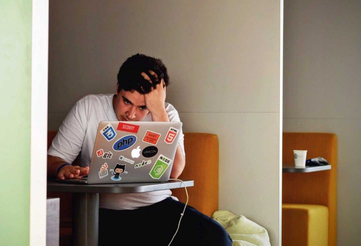 A young adult being stressed working on a computer