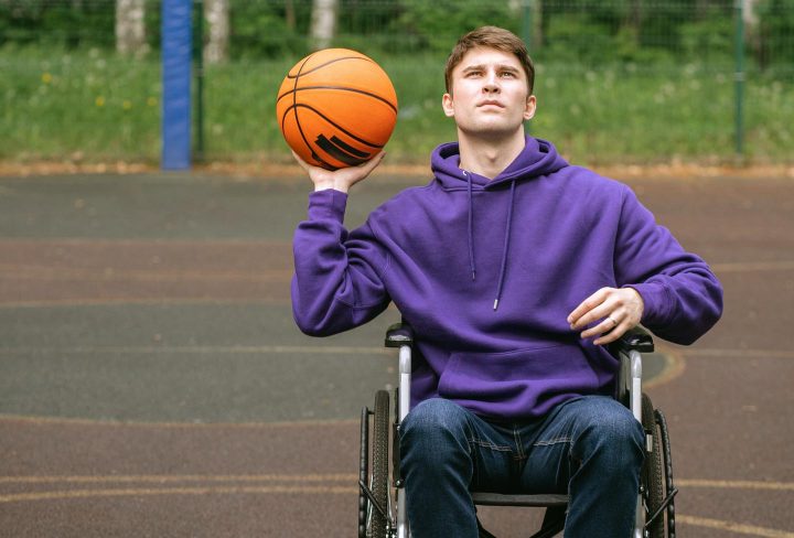 Um homem jogando basquete em uma cadeira de rodas
