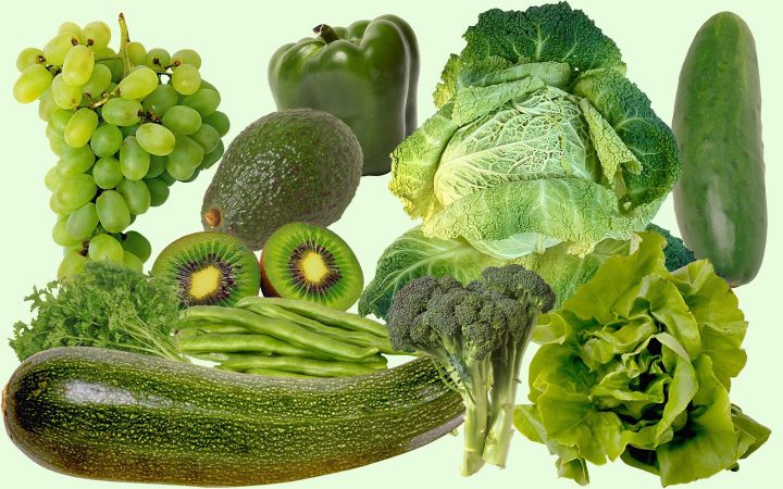 Uma variedade de frutas e vegetais verdes, incluindo abobrinha, pepino, alface, repolho, brócolis, vagem, pimentão, abacate, kiwi e uva.