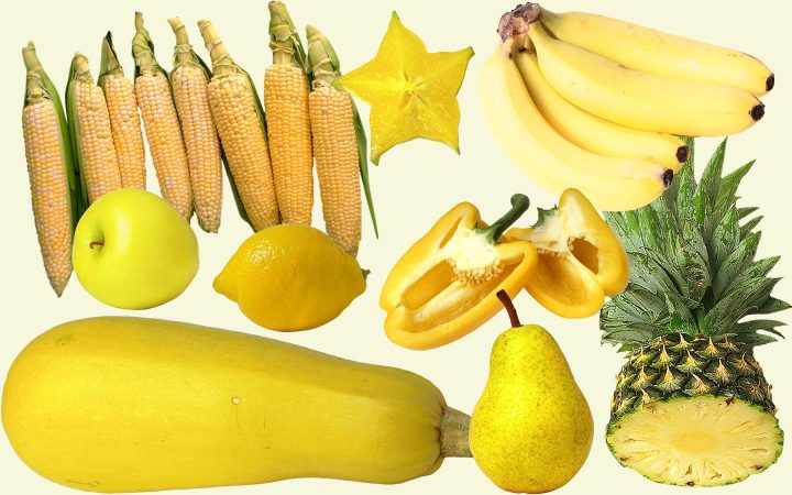 Uma variedade de frutas e vegetais amarelos, incluindo abobrinha, maçã, pêra, abacaxi, pimentão, banana, limão, carambola e espiga de milho.