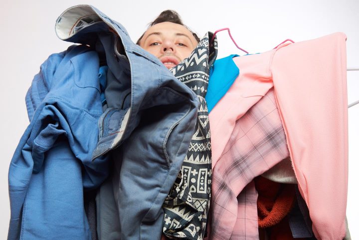 A man struggles with a pile of clothes