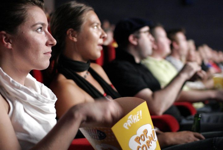 A lady snacking on popcorn inside a cinema - Photo by rpb1001 on Flickr https://www.flickr.com/photos/rpb1001/257368762/