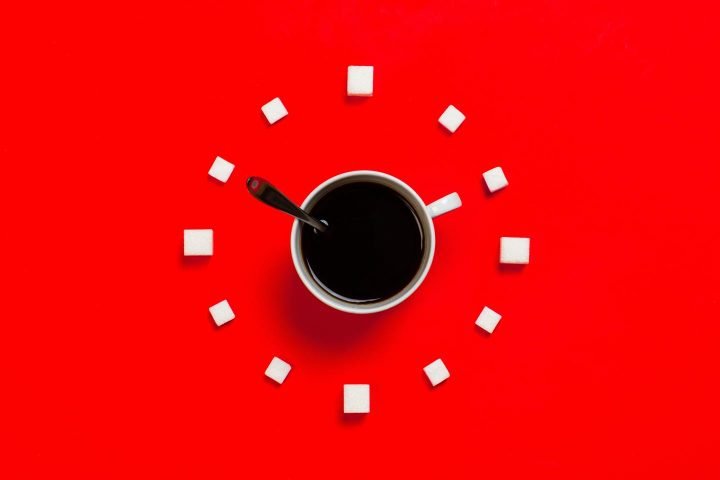 Um relógio simbolizado por uma xícara de café e cubos de açúcar.