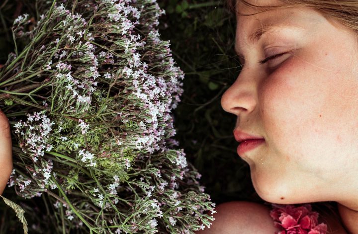 Uma menina cheirando uma flor de valeriana
