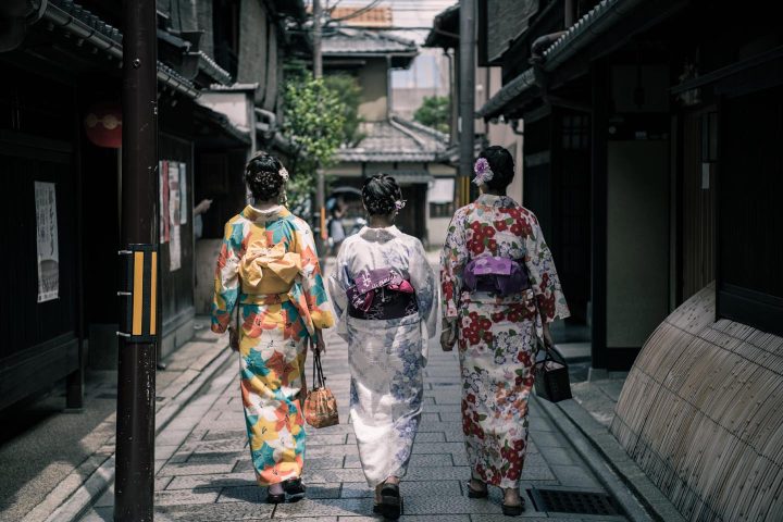 Three Japanese ladies in traditional outfit strolling a street