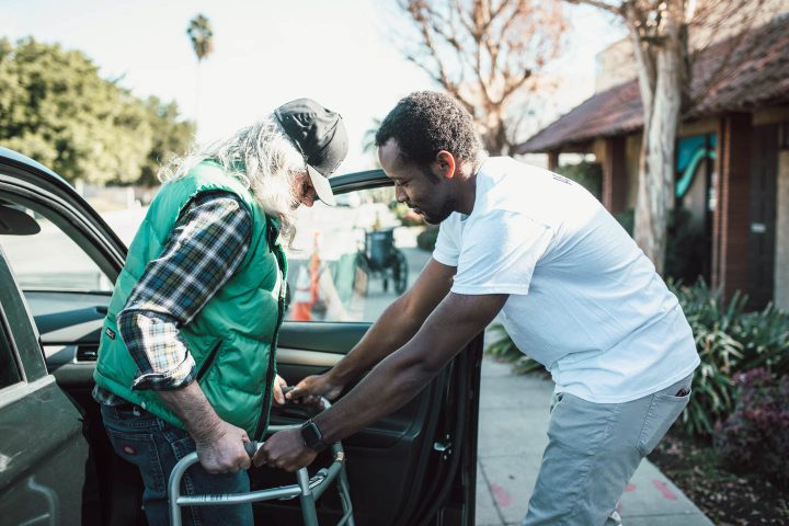 Helping a man getting out of the car with a walker
