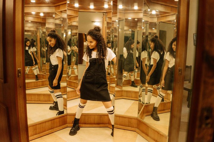 A teenager in a mirror room looking at her multiple images
