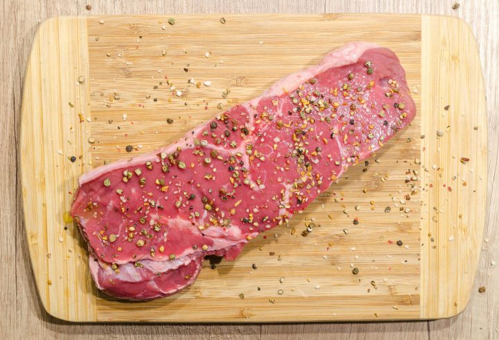 A piece of raw meat on a cutting board containing plenty of blood