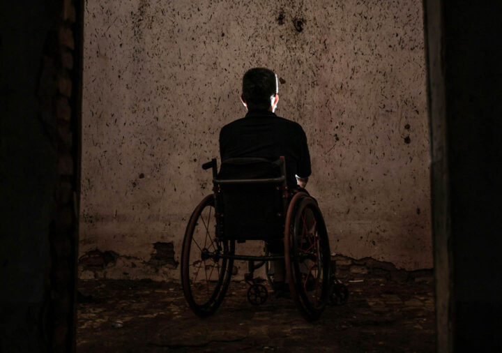 An elderly man sitting in a wheelchair in a bleak environment