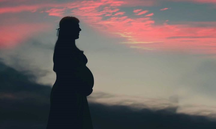 Uma mulher grávida no por do sol.