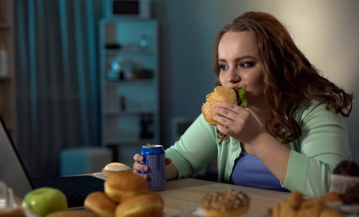 Uma mulher comendo junk food em excesso