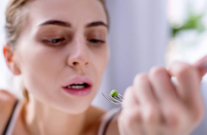 A girl with anorexia, being in anguish about eating a single pea