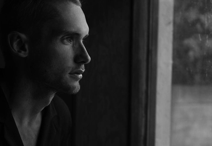A thoughtful person looking out the window and reflecting on life