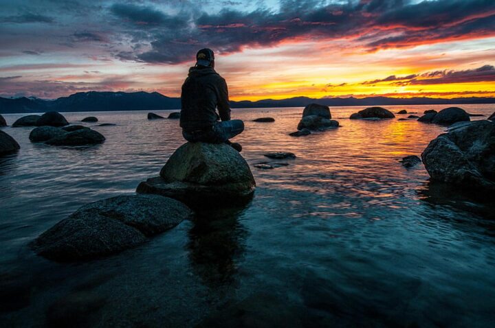 A young man watching the sunset on the beach and reflecting on his life