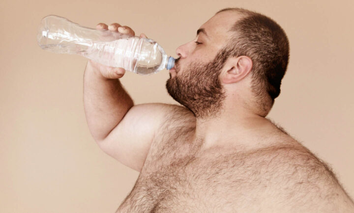 An obese man drinking water