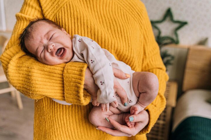 A baby crying in the arms of the mother