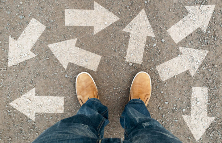 Feet of a man with arrows in all directions depicting options of choices