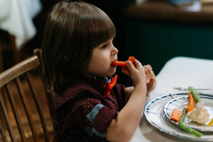A small girl eating vegetables