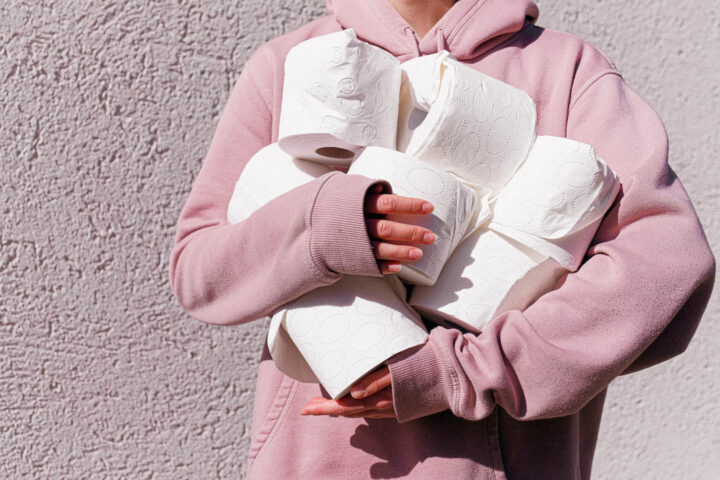 A woman hoarding a bunch of rolls of toilet paper