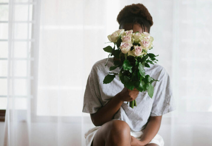 A shy teenage girl hiding behind a bouquet of roses