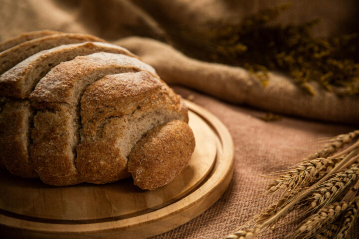 A loaf of whole wheat bread with some ears of wheat