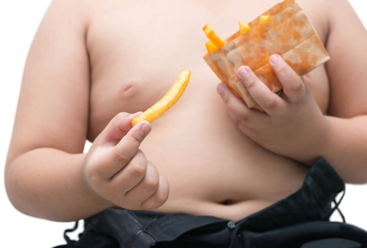 An obese boy eating french fries
