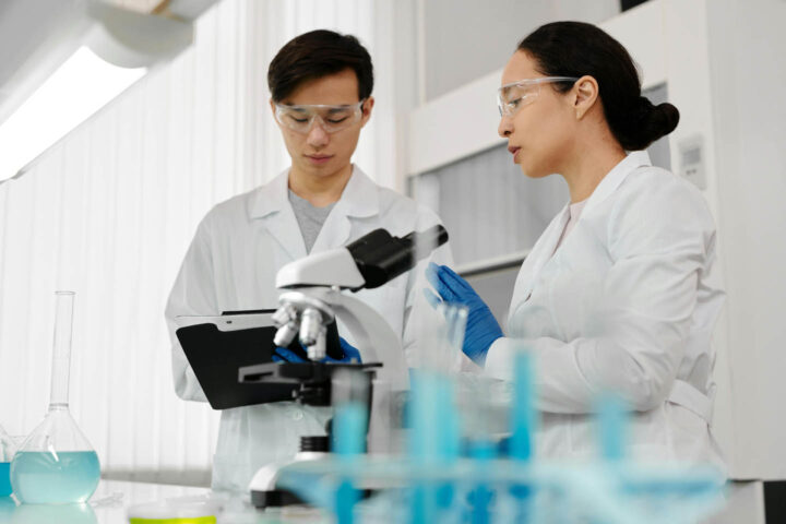 Two researchers with a microscope discussing the evidence
