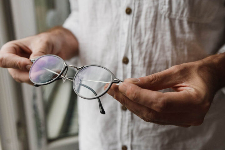A man holding a pair of glasses that are not right