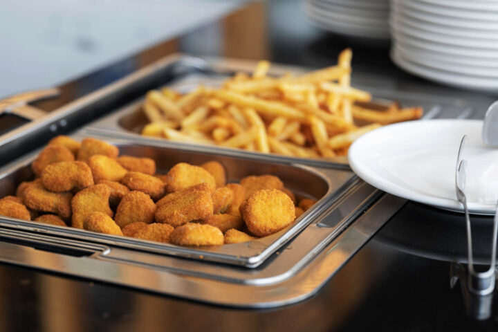 Chicken nuggets and pommes being served in a food counter